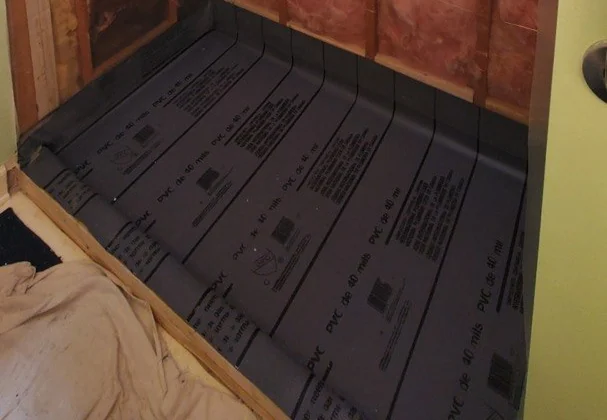 One of our showers mid-build: a 40 mil rubber pan liner laid over the shower floor and turned up the walls, with the drain set through it, before the cement base is poured