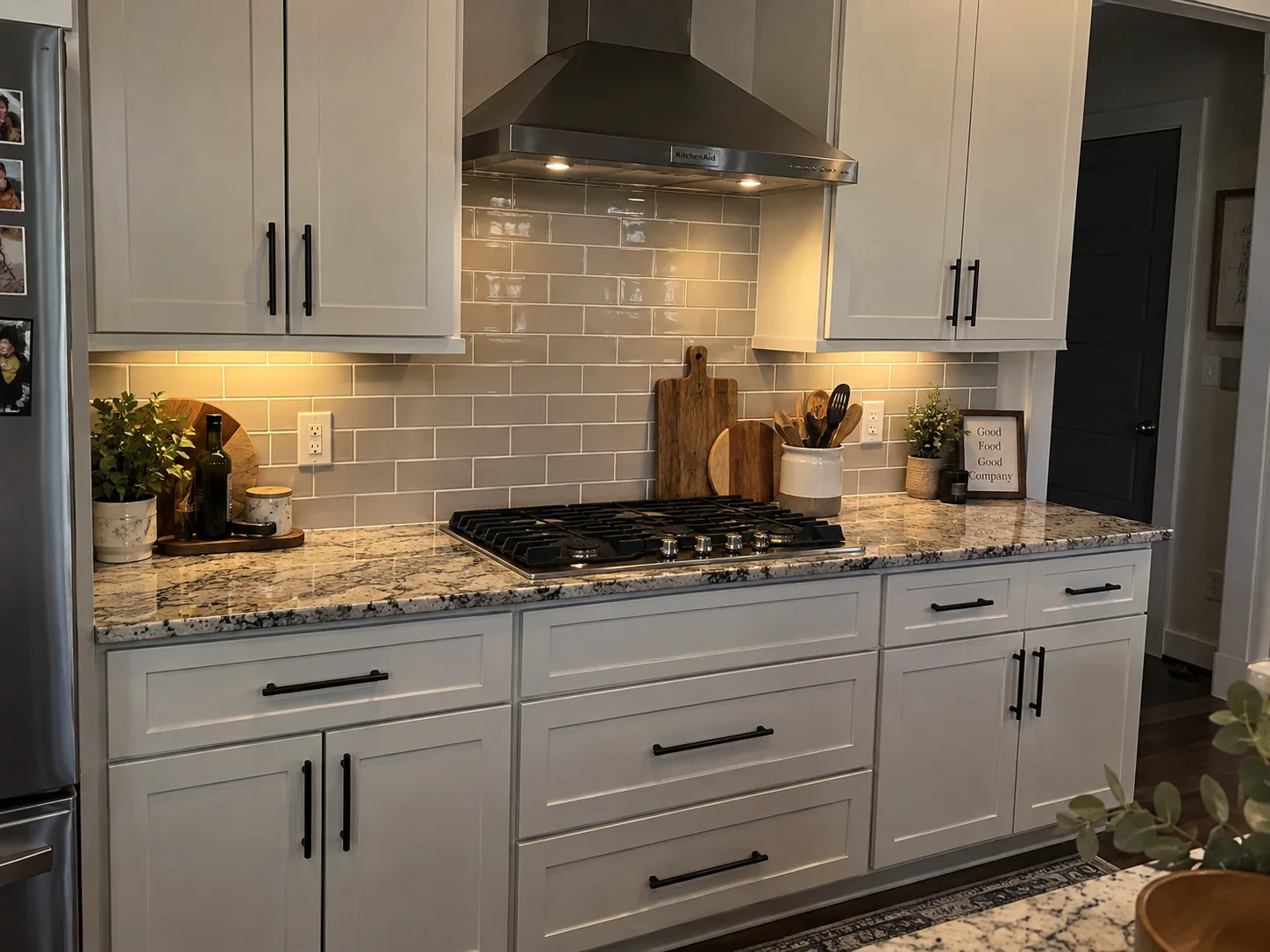 A tiled kitchen backsplash in glossy grey subway tile, carried the full run of the counter, up behind the range hood and cut around the outlets